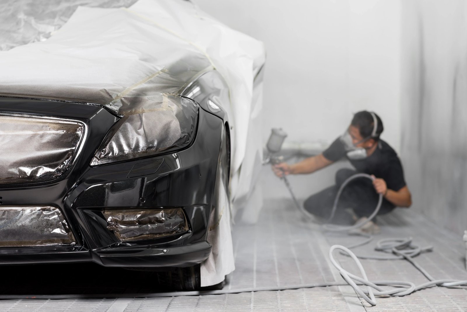 A red vehicle masked for refinishing in the Latrobe Auto Body spray booth